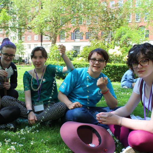 photo of group of young people young people sitting on crass with daisy chain